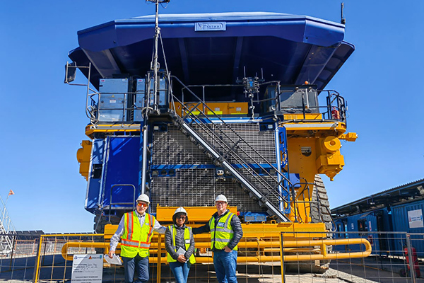 Aron Alberts and two others stand before the First Generation Hydrogen Hybrid large Mining Haul truck